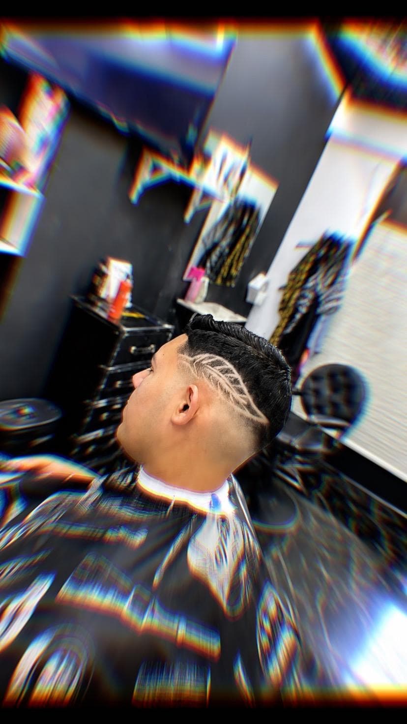 Hombre con corte degradado y diseño artístico afeitado en el lateral de su cabeza.